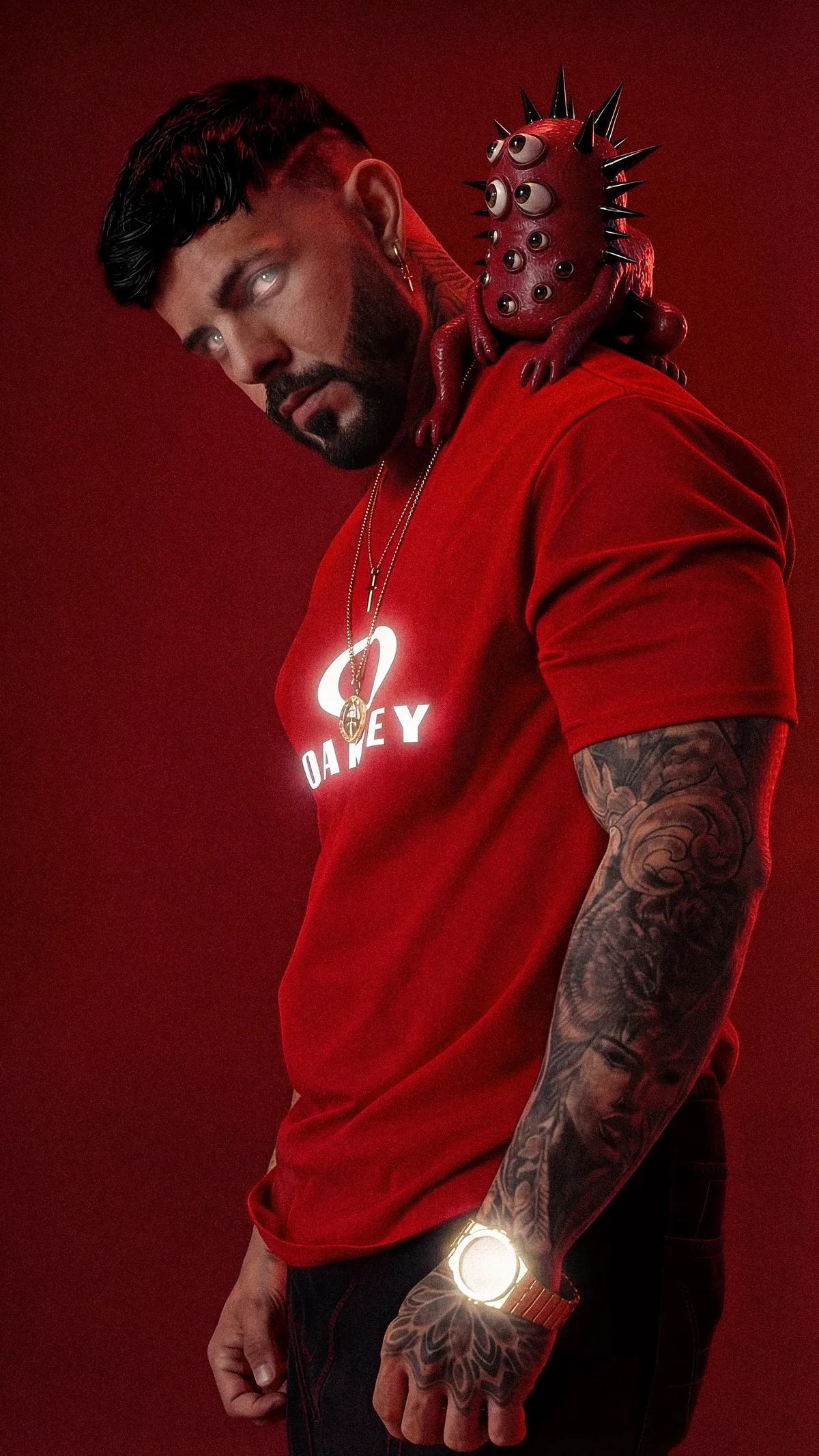HIDEKI de perfil con camiseta roja y una criatura de ojos sobre el hombro