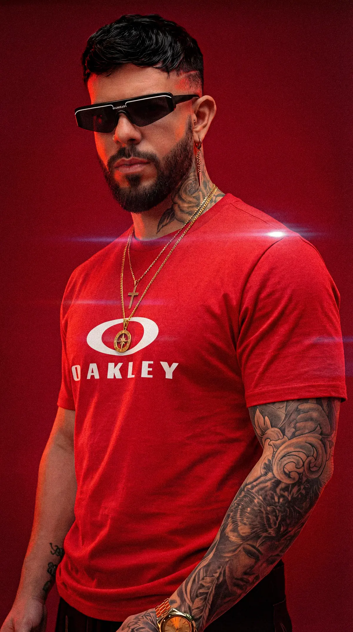 HIDEKI con camiseta roja Oakley y gafas negras sobre fondo rojo